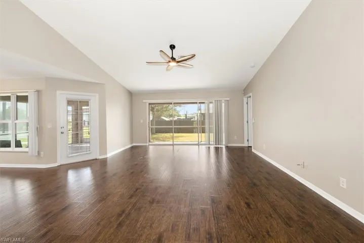 Unfurnished living room with vaulted ceiling, dark wood-style flooring, and a ceiling fan