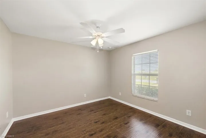 Unfurnished room with dark wood finished floors and a ceiling fan