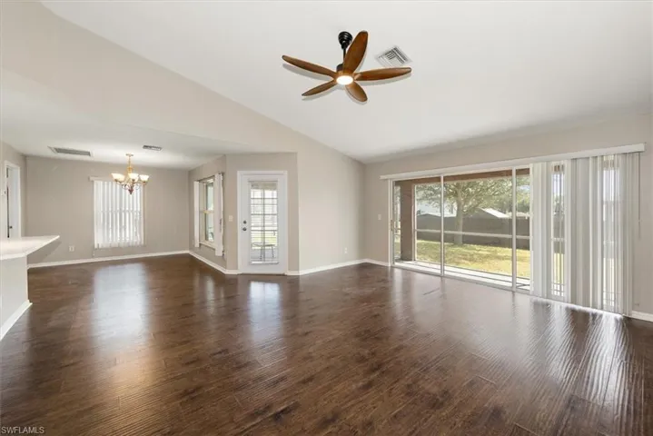 Unfurnished room featuring a chandelier and dark wood-style flooring