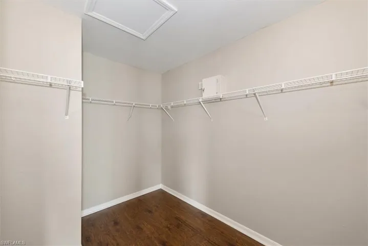 Spacious closet featuring dark wood-style floors and attic access