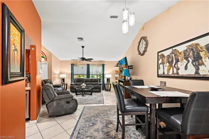Tiled dining area featuring ceiling fan and vaulted ceiling