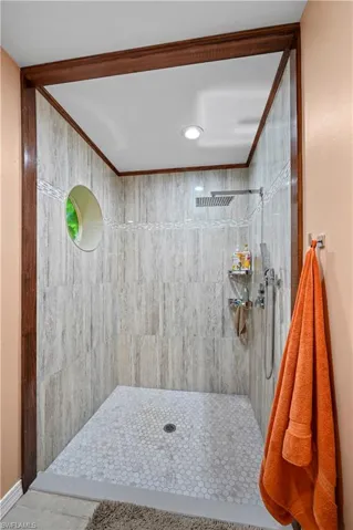 Bathroom with a tile shower, tile patterned flooring, and crown molding