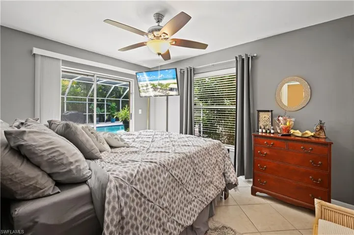 Bedroom featuring multiple windows, light tile patterned floors, ceiling fan, and access to exterior