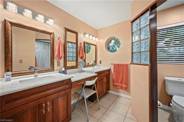 Bathroom featuring a healthy amount of sunlight, tile patterned flooring, vanity, and toilet