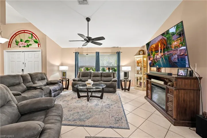 Tiled living room with vaulted ceiling and ceiling fan