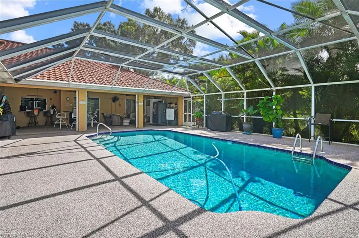 View of swimming pool featuring glass enclosure and a patio