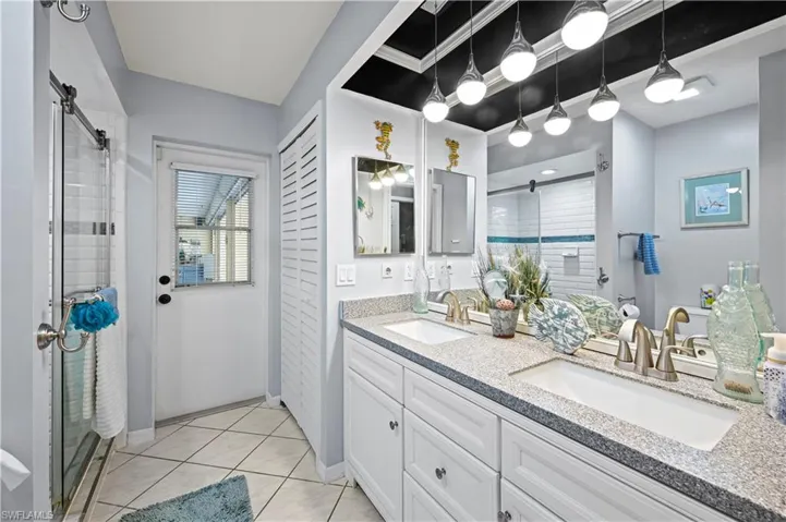 Bathroom with vanity, a shower with shower door, and tile patterned floors