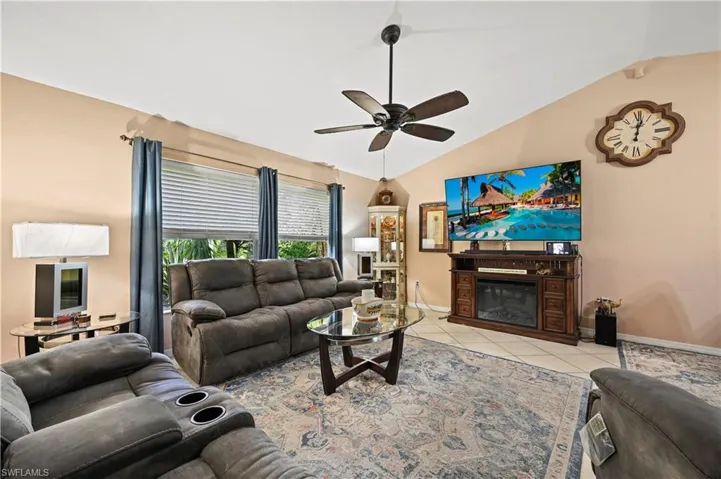 Tiled living room featuring lofted ceiling and ceiling fan