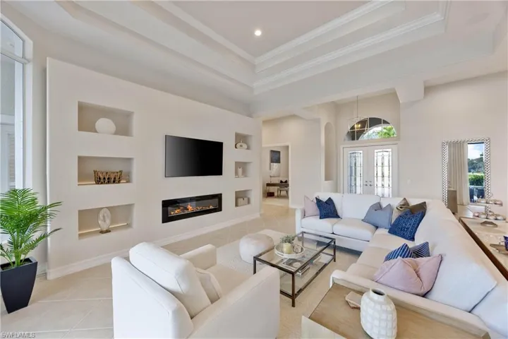 Living room featuring built in shelves, light tile patterned floors, arched walkways, french doors, and ornamental molding
