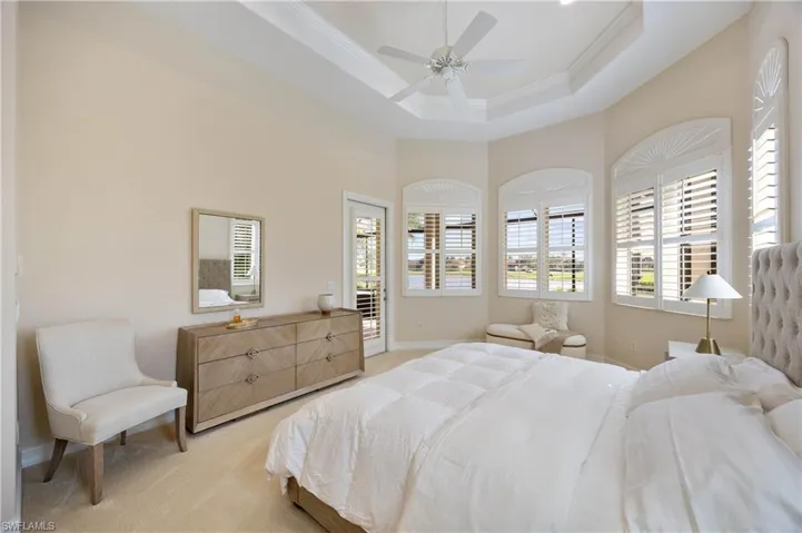 Bedroom with light colored carpet, access to exterior, ceiling fan, a tray ceiling, and ornamental molding