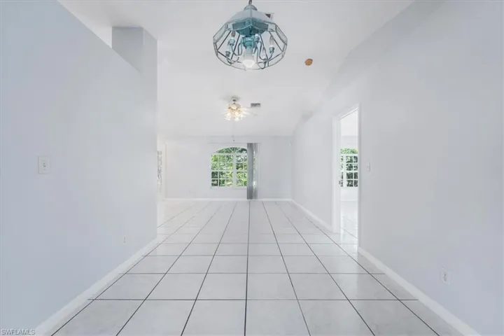 Empty room with tile patterned floors, vaulted ceiling, and ceiling fan
