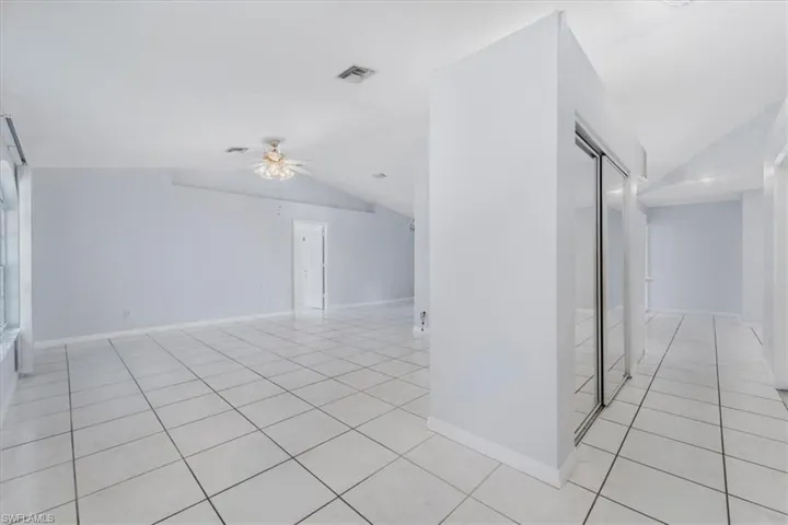 Unfurnished room with light tile patterned flooring, lofted ceiling, and a ceiling fan