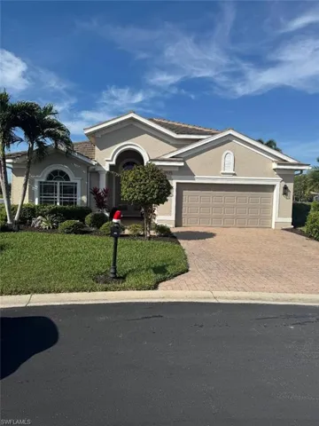 Ranch-style house with stucco siding, decorative driveway, a front lawn, and an attached garage