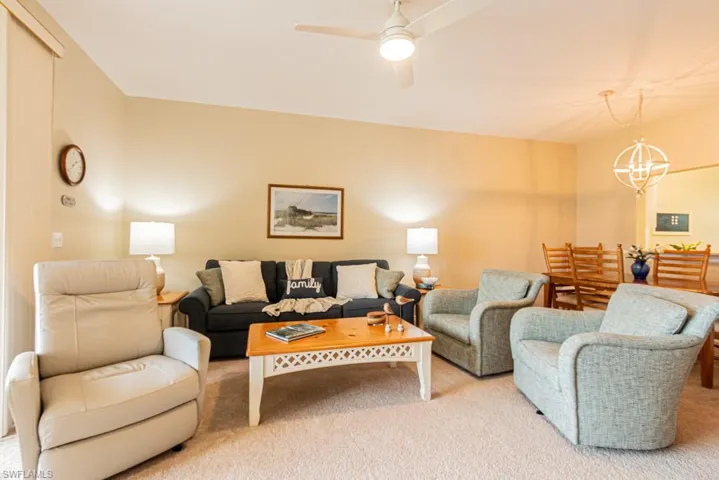 Living room featuring ceiling fan with notable chandelier