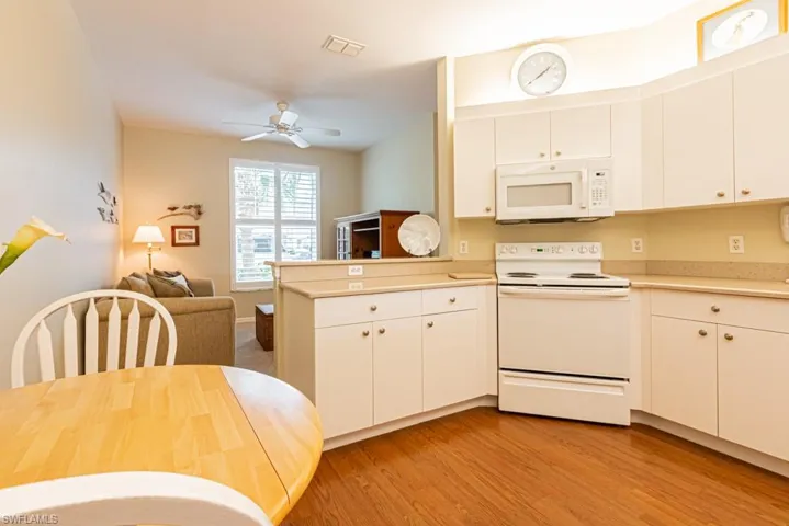 Kitchen with light countertops, visible vents, white appliances, light wood-style floors, and a peninsula