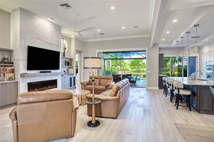 Kitchen featuring stainless steel refrigerator with ice dispenser, light stone counters, tasteful backsplash, beamed ceiling, and light wood-type flooring