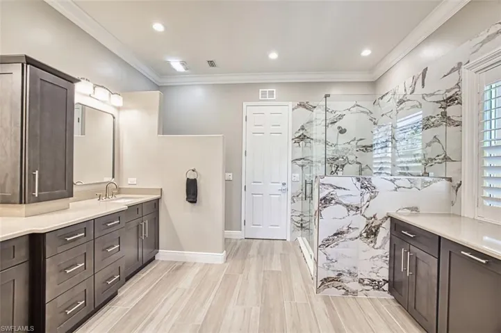 Bathroom featuring vanity and a marble finish shower