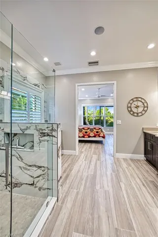 Bedroom featuring light colored carpet, crown molding, and a ceiling fan