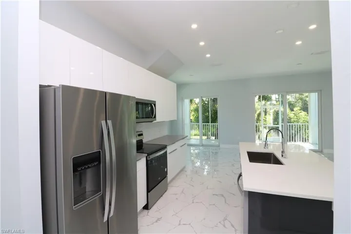 Kitchen featuring sink, appliances with stainless steel finishes, and white cabinetry