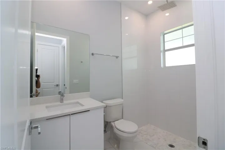 Bathroom featuring vanity, toilet, and a tile shower