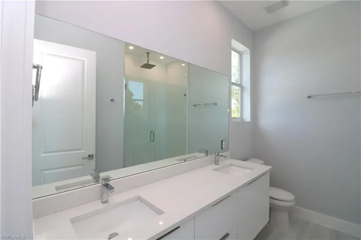 Bathroom featuring toilet, a shower with door, and vanity