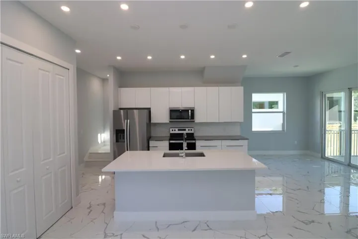 Kitchen featuring white cabinets, appliances with stainless steel finishes, sink, an island with sink, and tasteful backsplash