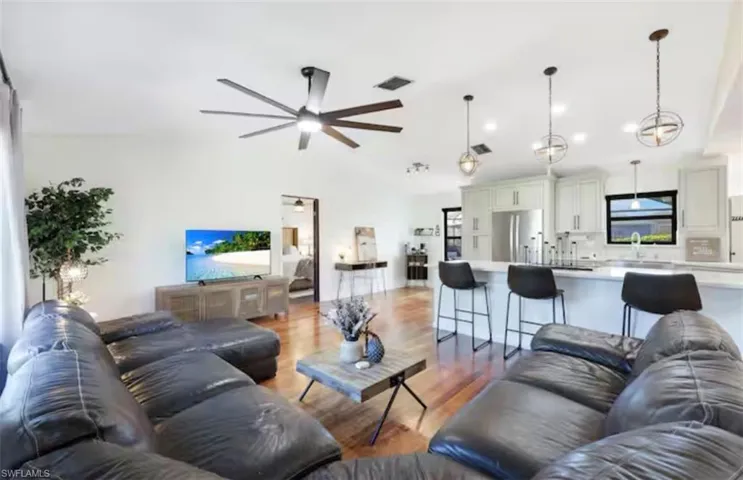 Living area with lofted ceiling, light wood-style floors, and a ceiling fan
