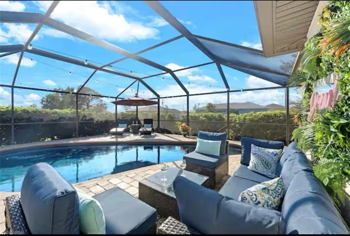 Swimming pool featuring a sunroom, a lanai, a patio area, and an outdoor living space