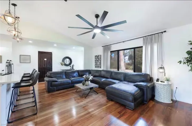 Living room with dark wood-style floors, lofted ceiling, and ceiling fan