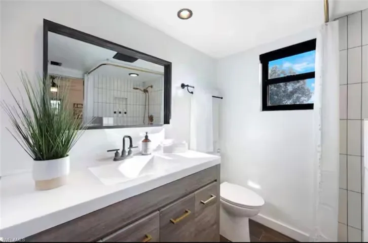 Bathroom featuring vanity, a shower, and dark wood finished floors