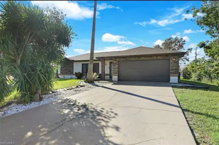 Ranch-style home featuring an attached garage, concrete driveway, and a front yard