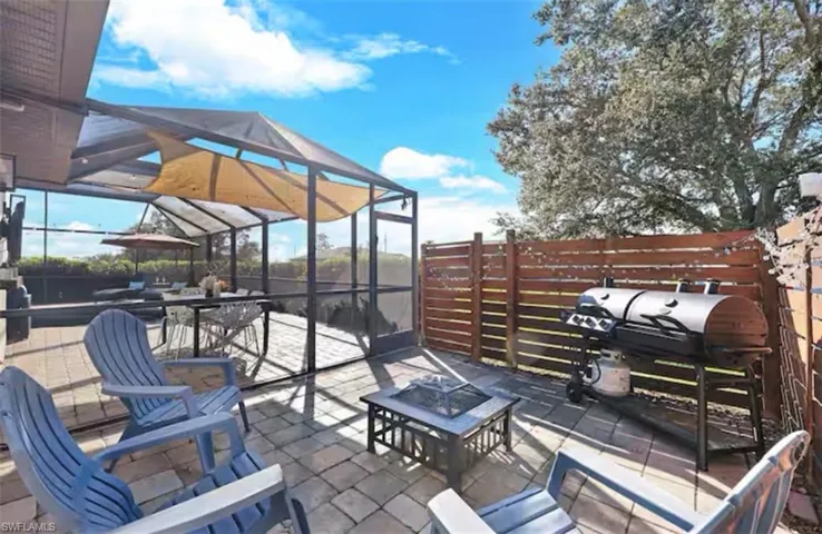 View of patio featuring a sunroom, glass enclosure, a grill, and a fire pit