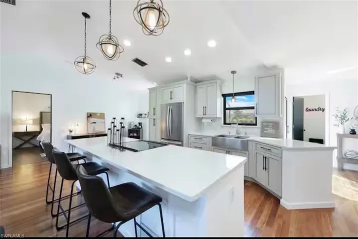 Kitchen featuring a kitchen breakfast bar, stainless steel refrigerator, dark wood-style flooring, and pendant lighting