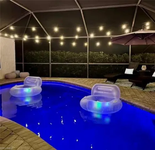 Pool at twilight with an outdoor pool, a sunroom, and glass enclosure