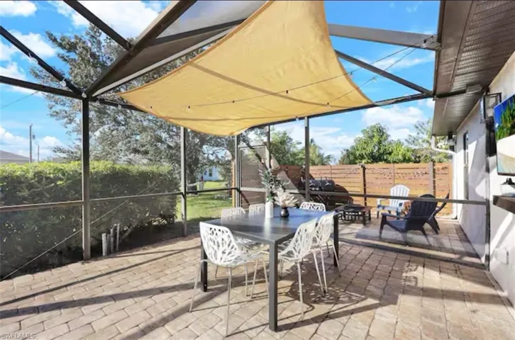 View of patio featuring a sunroom, glass enclosure, and outdoor dining area