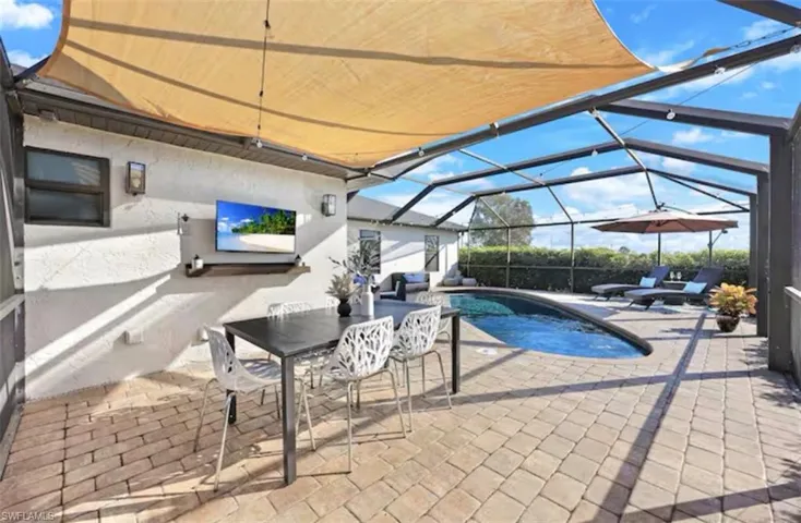 Outdoor pool with a patio area, a sunroom, outdoor dining area, and a lanai