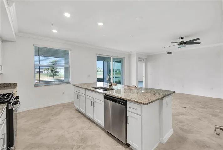 Kitchen with ceiling fan, stainless steel appliances, a center island, sink, and white cabinets