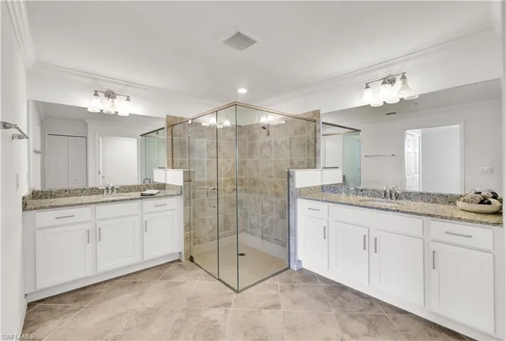 Bathroom with a shower with shower door, tile flooring, ornamental molding, and vanity