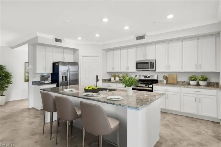Virtually Staged Kitchen with light tile floors, white cabinetry, a center island with sink, and stainless steel appliances