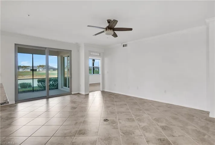 Tiled empty room featuring ceiling fan, a water view, and ornamental molding
