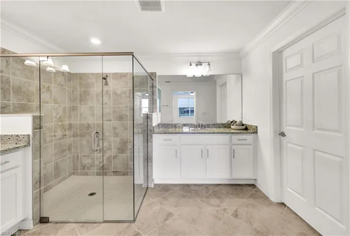 Bathroom featuring a shower with door, tile floors, crown molding, and vanity