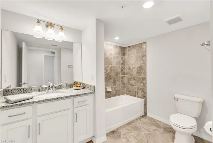 Full bathroom featuring tiled shower / bath, vanity, toilet, and tile floors