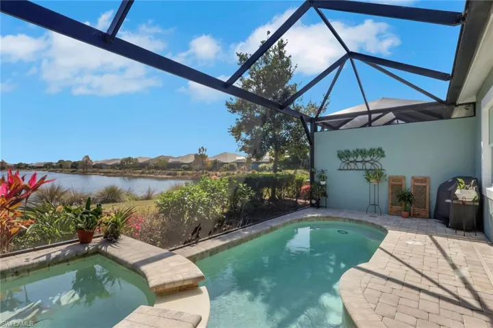 Swimming pool with glass enclosure, a patio area, a sunroom, a residential view, and a water view