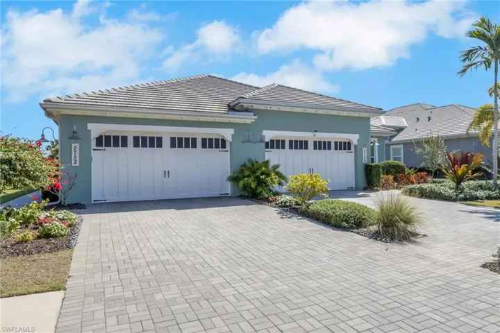 View of front facade with driveway, stucco siding, and a tiled roof