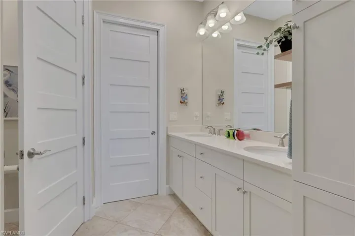 Full bath featuring double vanity and light tile patterned floors