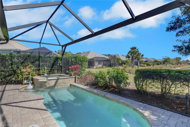 Relaxing pool / spa with glass enclosure, a sunroom, and a patio
