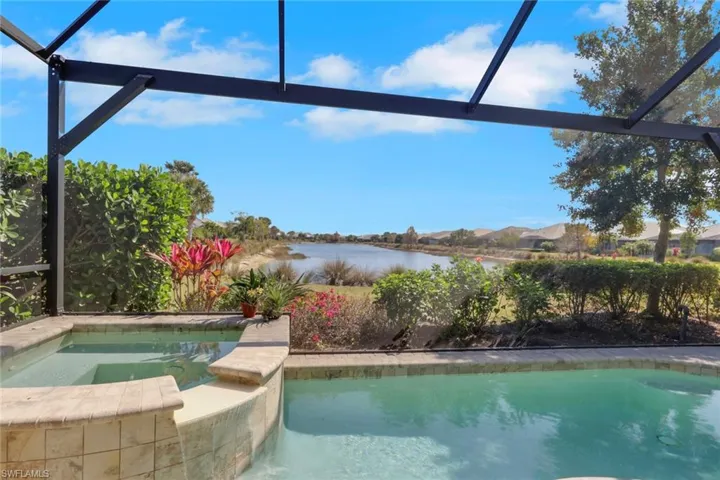 Combined pool / hot tub featuring glass enclosure, a water view, and a sunroom