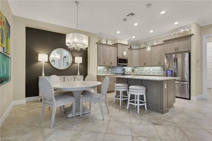 Kitchen featuring stainless steel appliances, a center island with sink, light stone countertops, a kitchen breakfast bar, and decorative backsplash