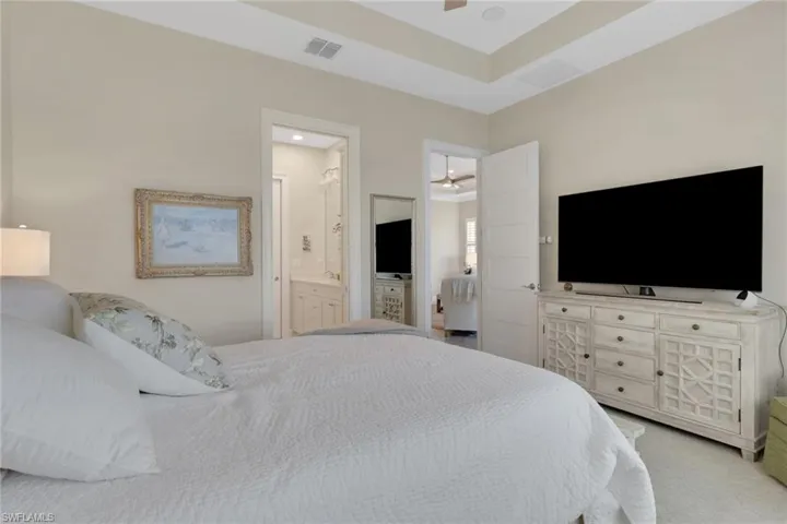 Bedroom with light colored carpet, ceiling fan, and ensuite bathroom
