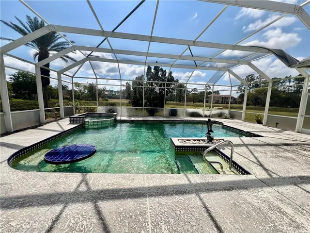 View of swimming pool featuring screen enclosure, a patio area, and a pool with connected hot tub